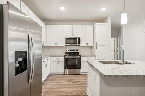 A modern kitchen with a stainless steel refrigerator and white cabinets.