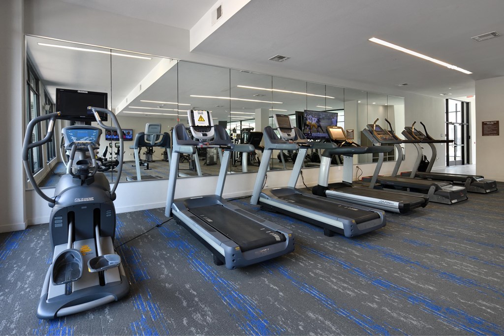 A gym with treadmills, elliptical machines, and other exercise equipment.