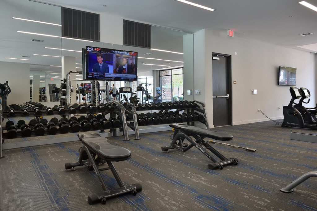 A gym with a television screen showing a news program.
