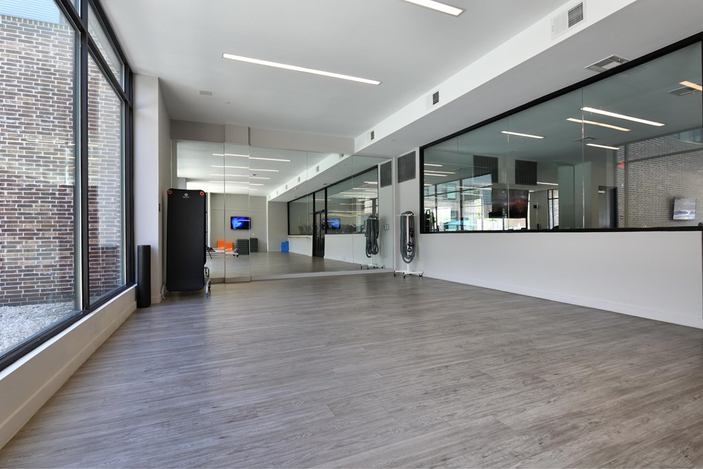 A long hallway with a black speaker on the left and glass walls on the right.