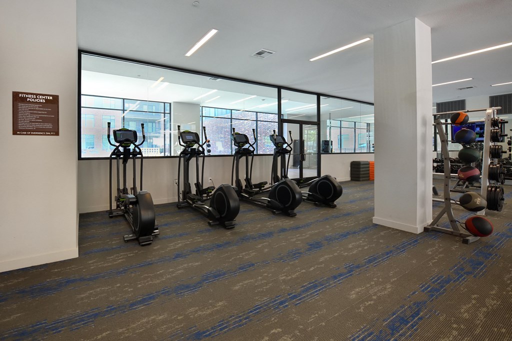A gym with a variety of exercise equipment including treadmills, stationary bikes, and weight machines.