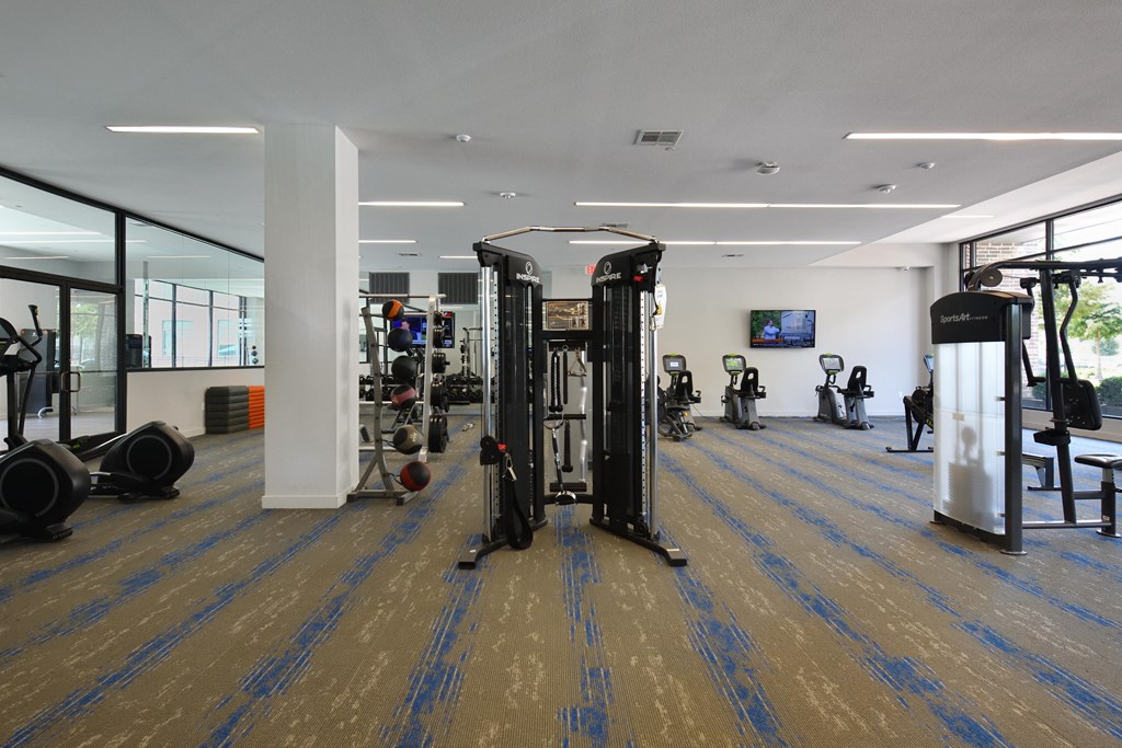 A gym with a variety of equipment including treadmills, weights, and exercise machines.