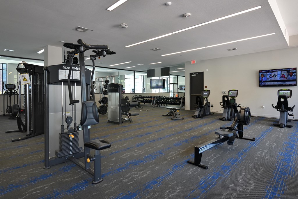 A gym with a variety of equipment including treadmills, weights, and exercise machines.