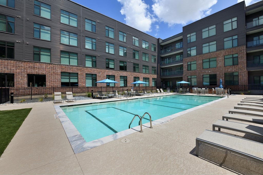A large swimming pool is surrounded by sun loungers and umbrellas.