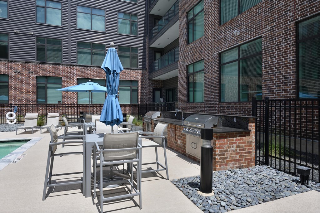 A patio with chairs and an umbrella in front of a brick building.