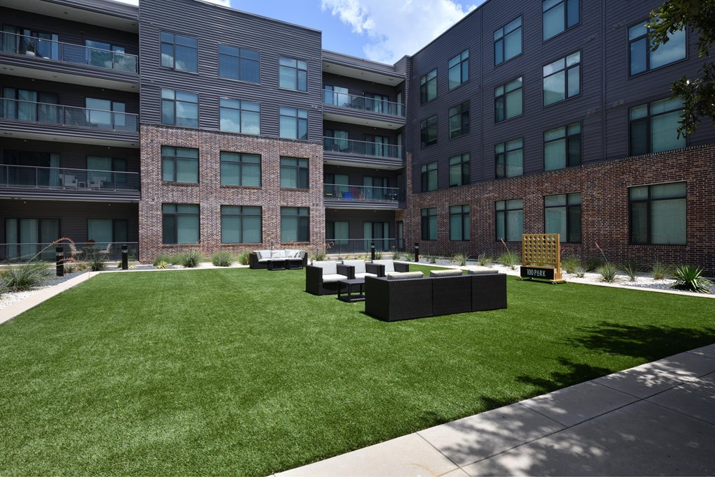 A grassy courtyard is surrounded by two brick buildings.