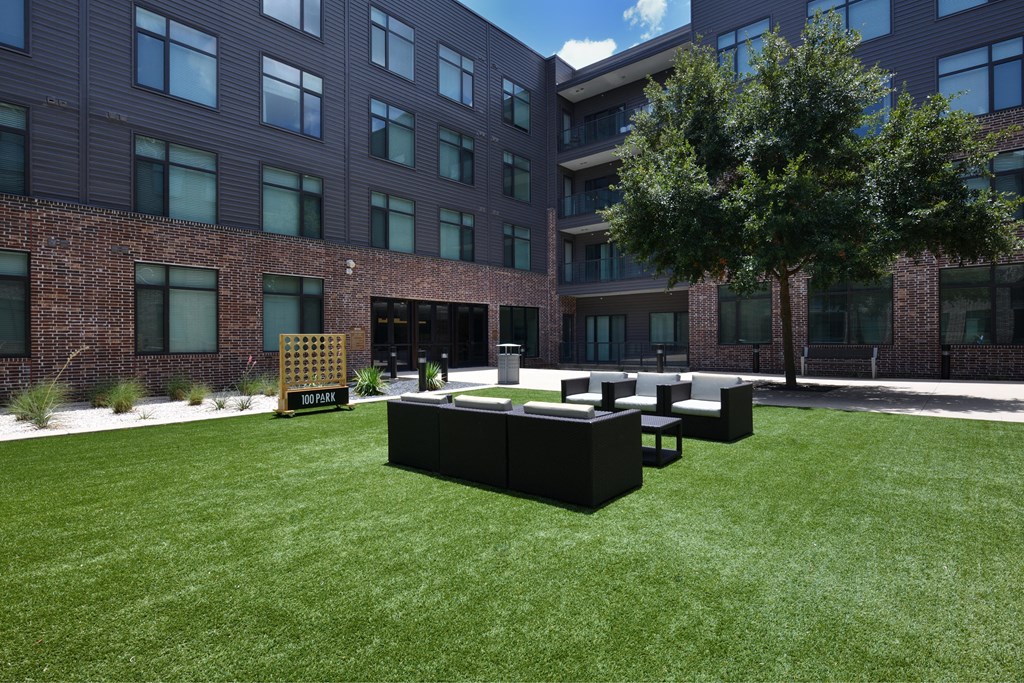 A black sculpture sits on a lawn in front of a brick building.