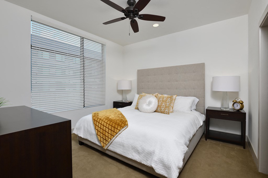 A bedroom with a bed, nightstands, and a ceiling fan.