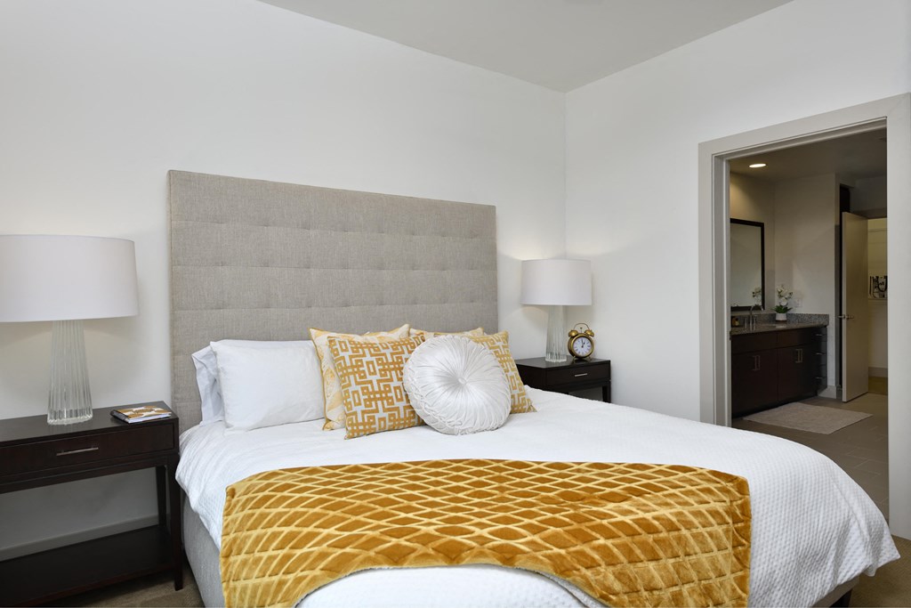 A bedroom with a bed, nightstands, and lamps.