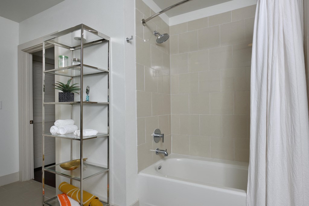 A white bathroom with a white tub and a white shower curtain.