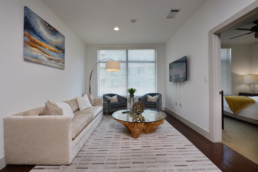 A living room with a white couch and a painting on the wall.