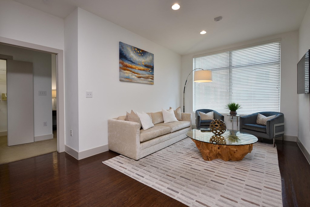 A living room with a white couch and a painting on the wall.