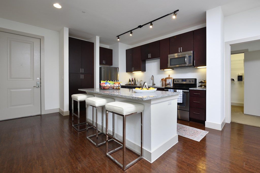 A kitchen with a white island and bar stools.