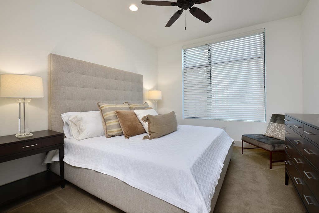 A bedroom with a large bed and a ceiling fan.
