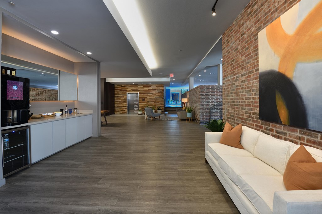 A modern kitchen with a white countertop and a white couch with orange pillows.
