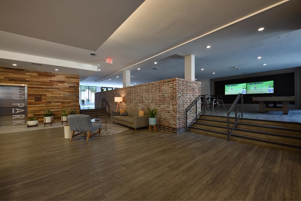 A modern living room with a wooden floor and a brick wall.