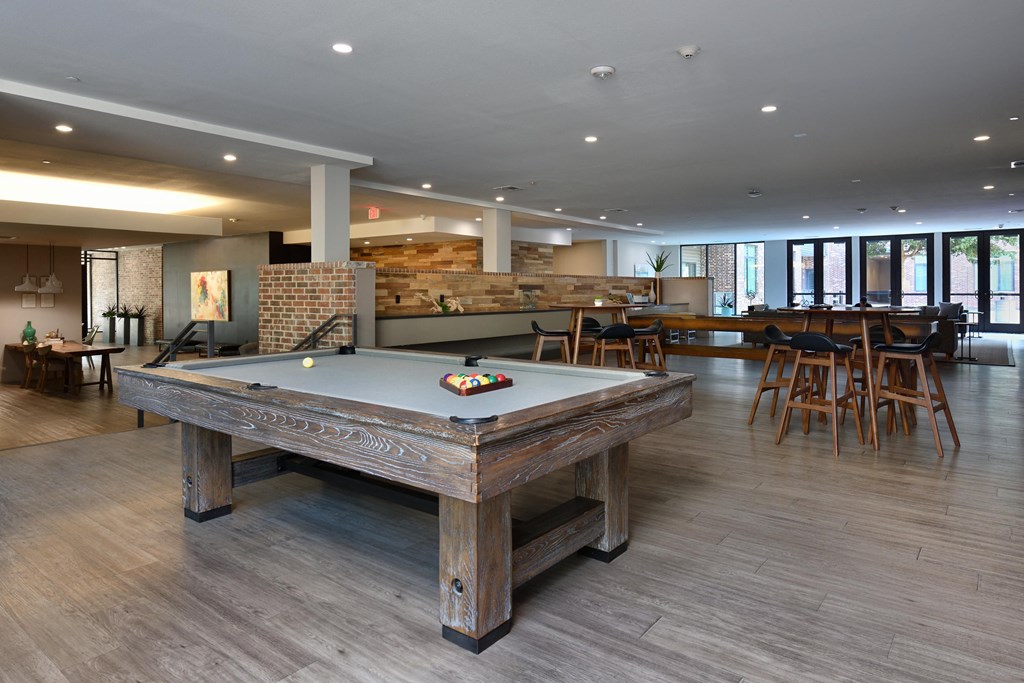 A pool table in a room with wooden floors and a brick wall.