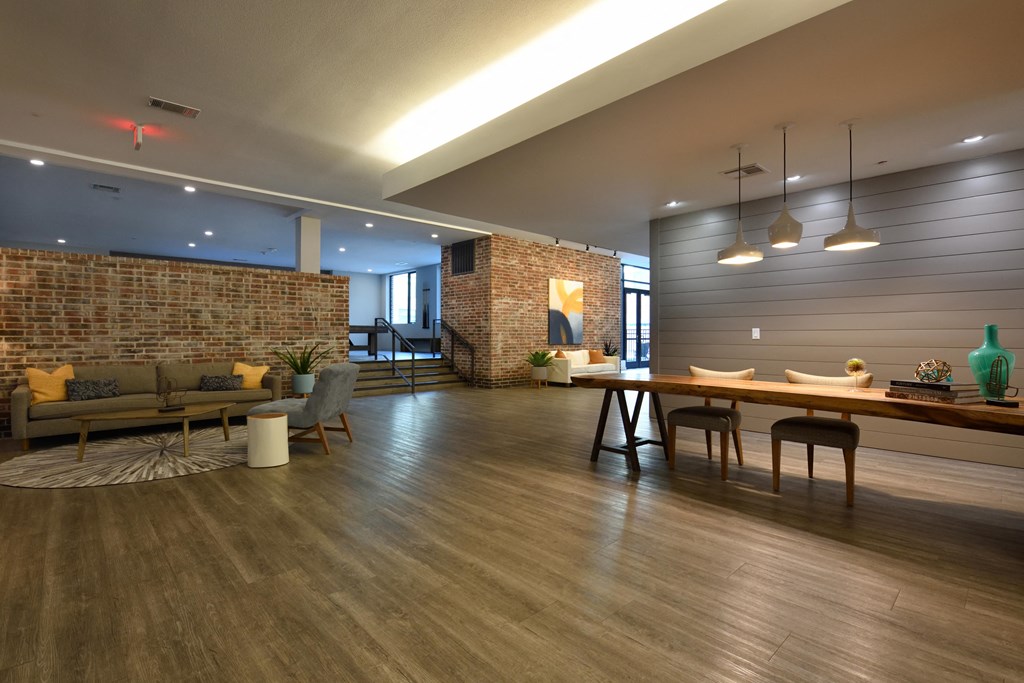 A modern living room with a brick wall and wooden floors.