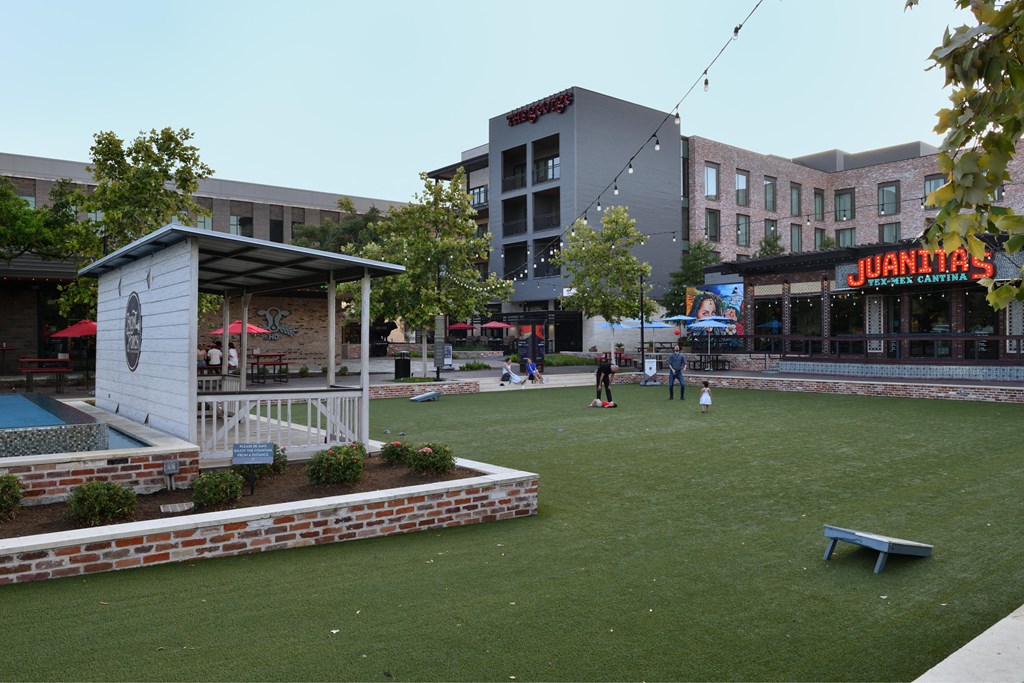 A small white building with a red roof is in the middle of a grassy area.