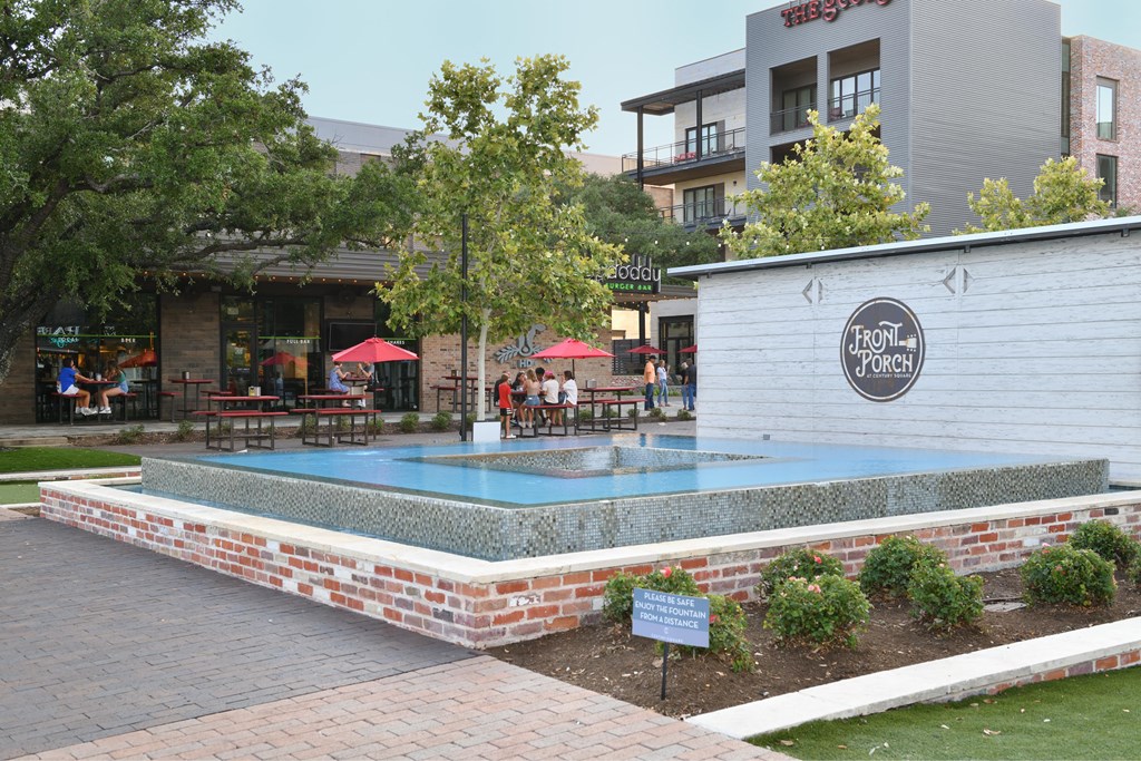 A small pool surrounded by a brick border with a sign that says "Front Porch".