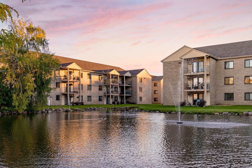 a pond in front of a building with a fountain