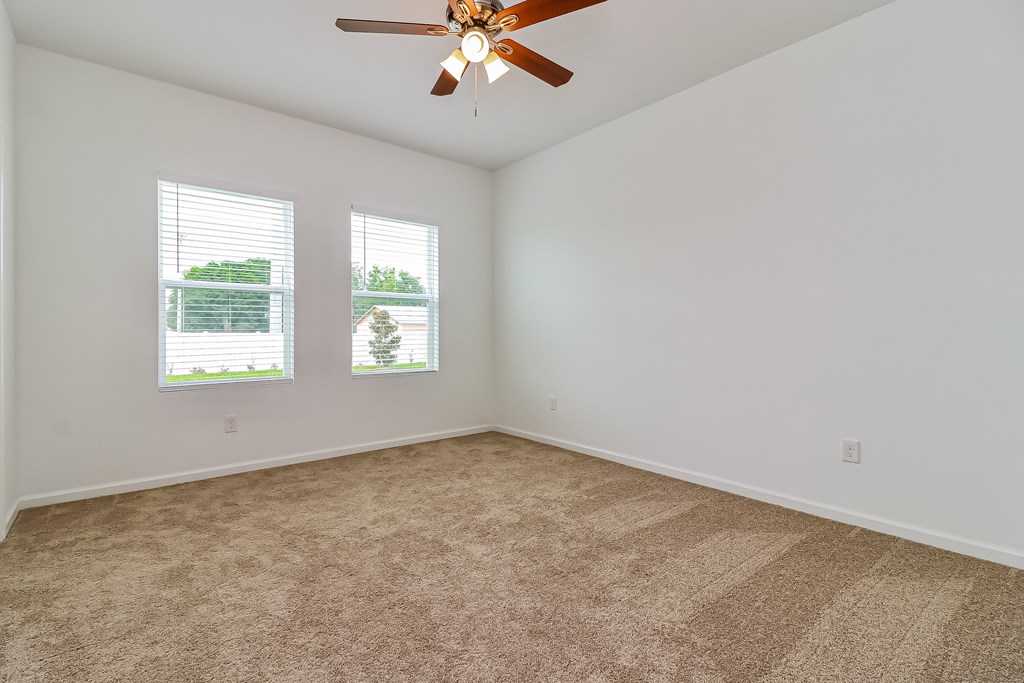 A room with a ceiling fan and carpeted floor.