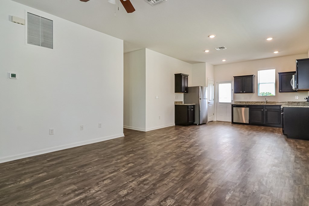 A spacious kitchen with dark wood floors and modern appliances.