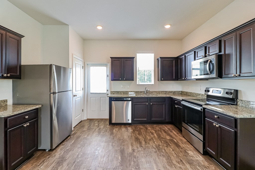 A kitchen with dark wood cabinets and stainless steel appliances.