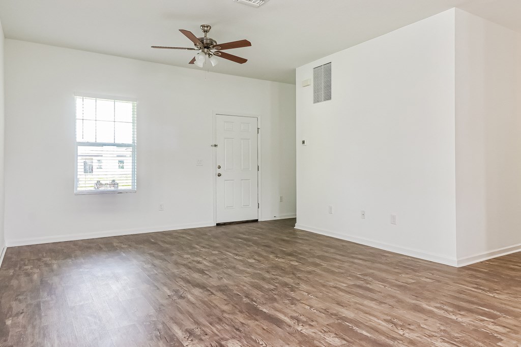 A room with a ceiling fan and a window with blinds.