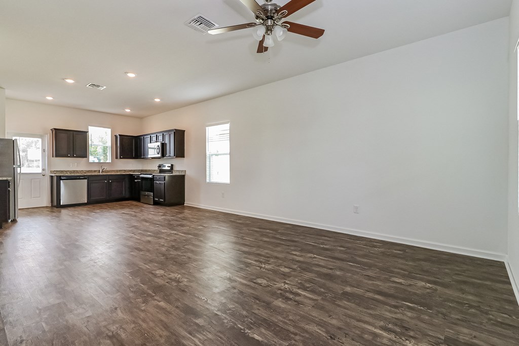 A spacious room with a ceiling fan and wooden flooring.