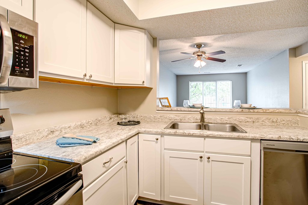 a kitchen with white cabinets and a sink and a ceiling fan