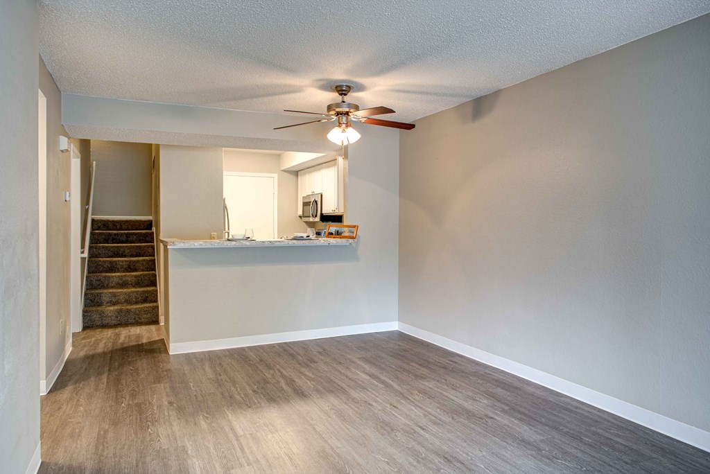the living room and kitchen of an empty house with a ceiling fan