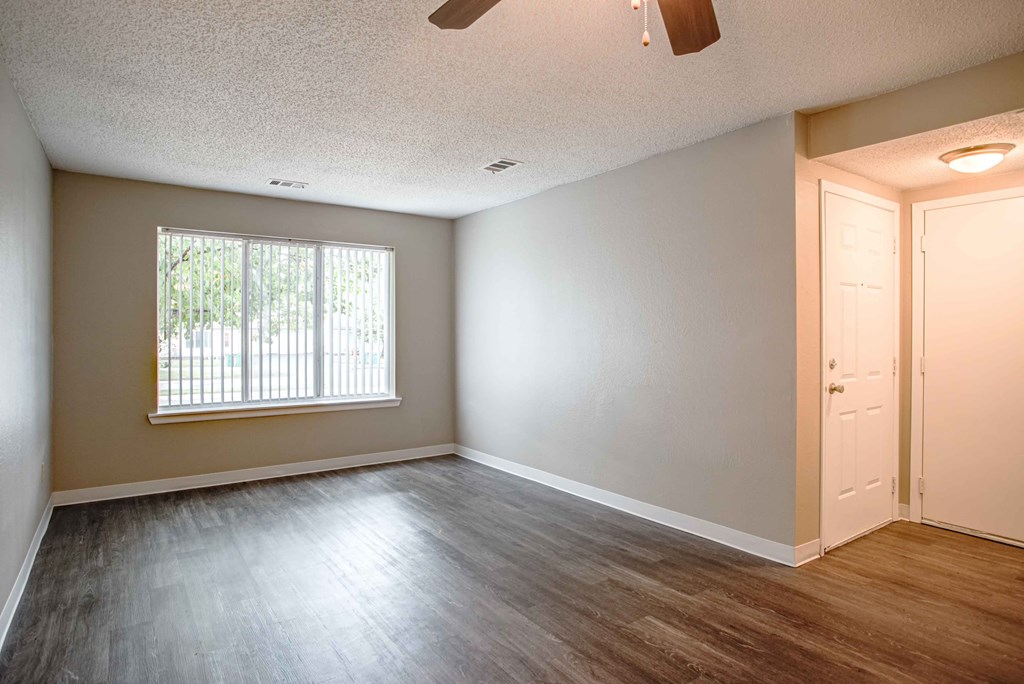 an empty living room with wood floors and a window