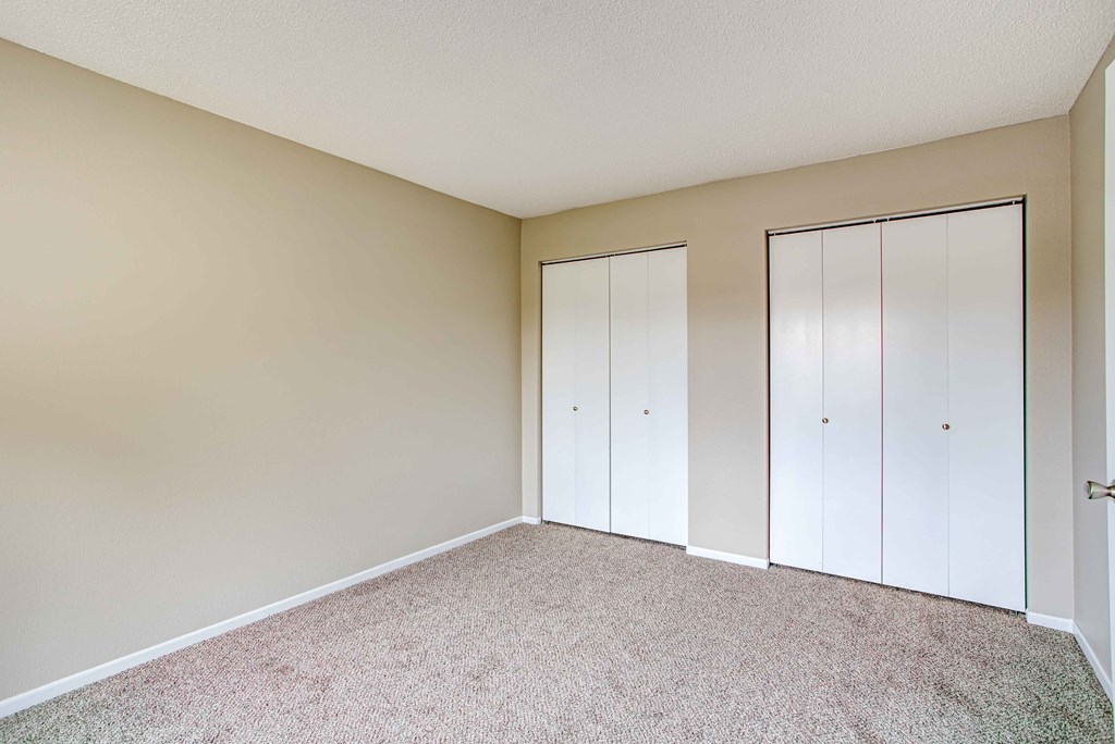 a bedroom with white closets and carpeting