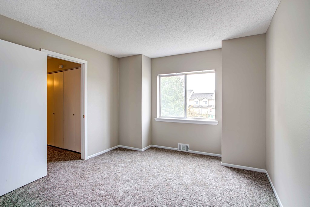 an empty room with a window and a door to a closet