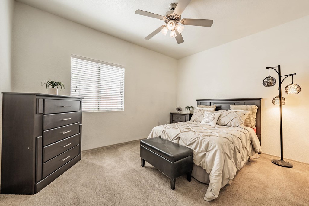 One-Bedroom Apartments in West Phoenix, AZ - Del Mar - Furnished Bedroom with Plush Carpet Flooring, High Ceilings, Windows, and a Ceiling Fan