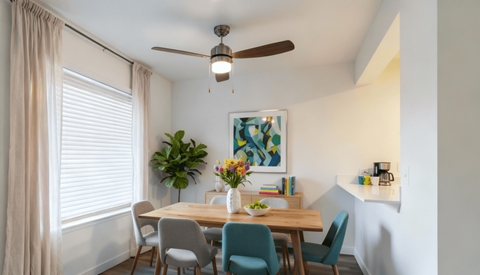 Pet-Friendly Apartments in Everett, WA - Woodbrook - Dining Area With A Wooden Table, Upholstered Chairs, Large Window, Colorful Wall Art, And Kitchen Breakfast Bar.