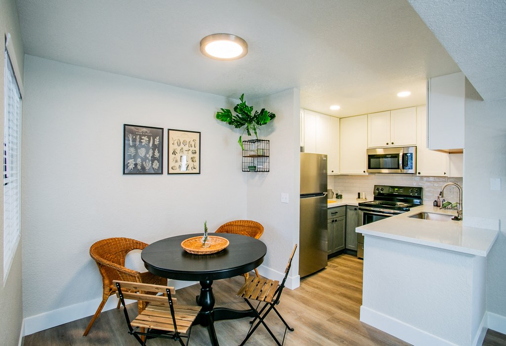 a dining area with a table and chairs and a kitchen with stainless steel appliances