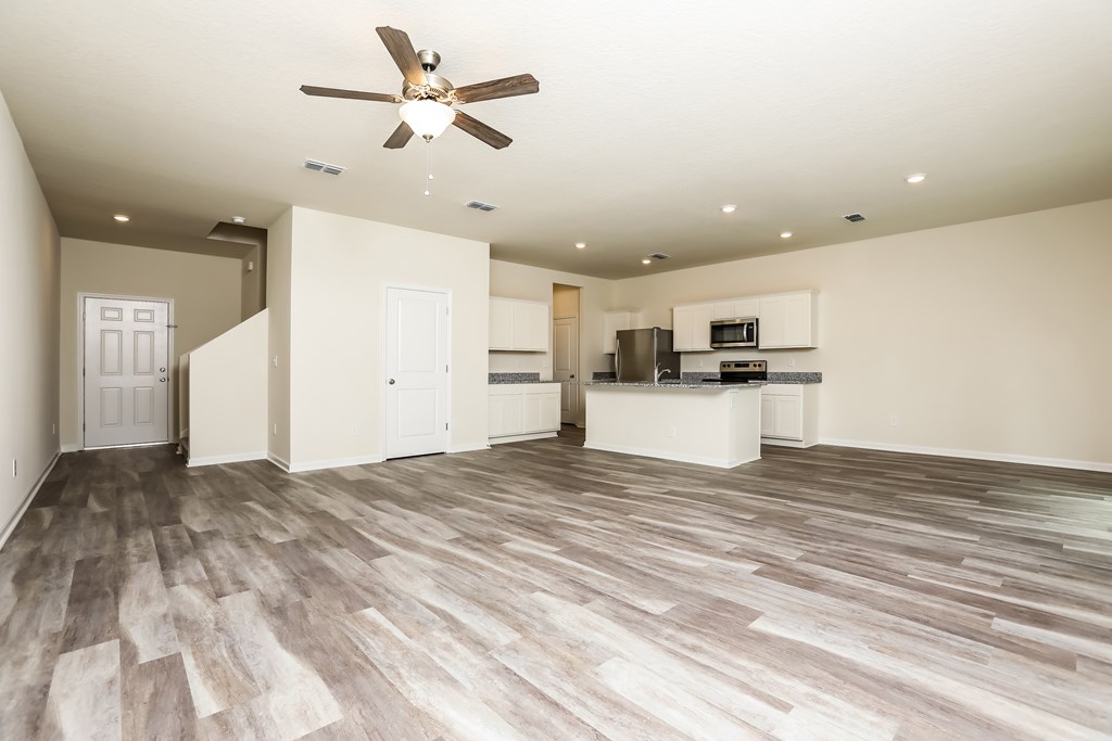A spacious room with a ceiling fan and lighting fixtures.
