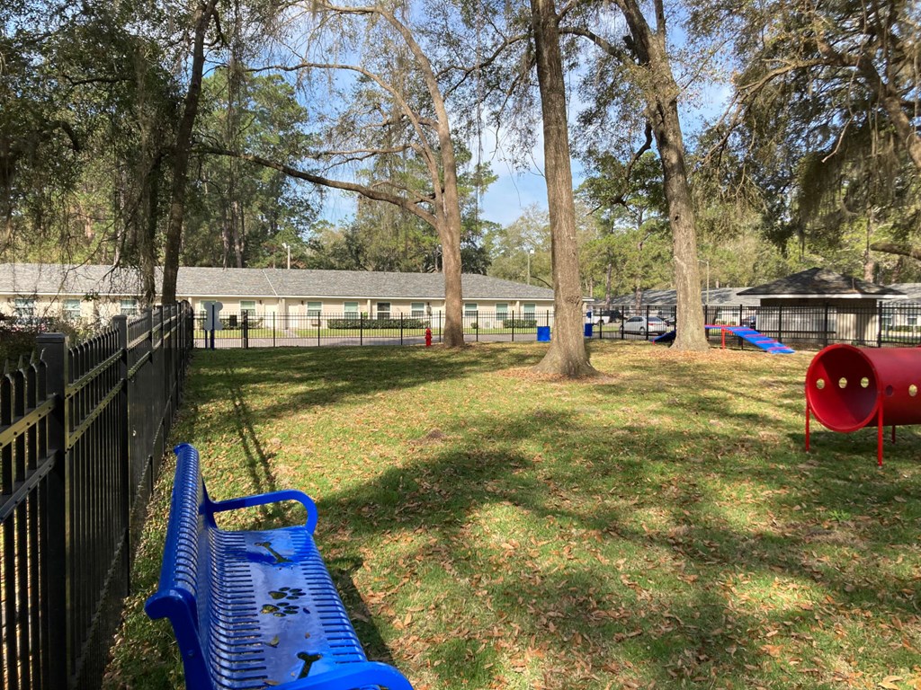 Addison Lane Apartment homes in Gainesville Florida photo of photo of a large grassy area with a swing set and a bench in front of a fence