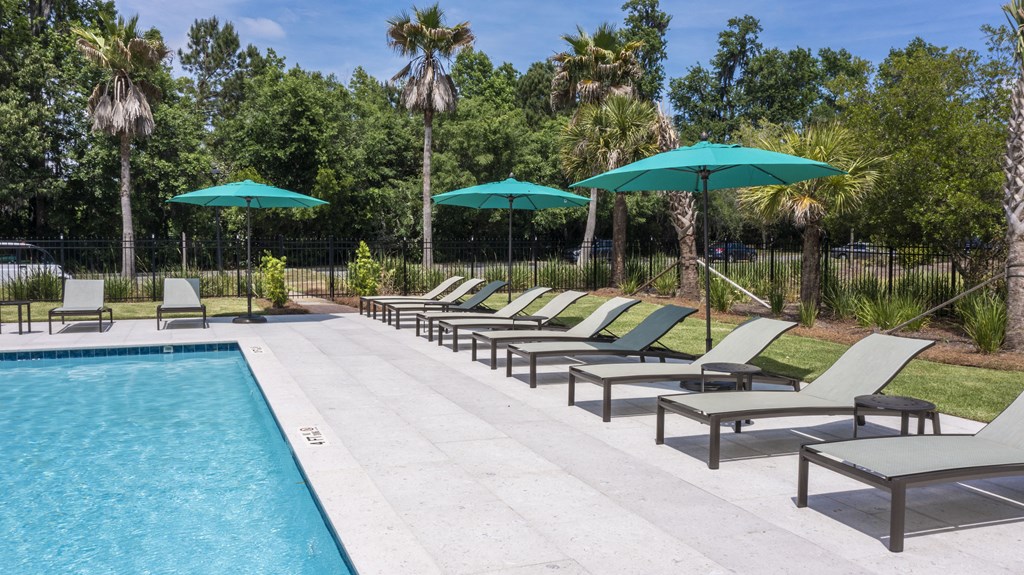 a pool with chaise lounge chairs and umbrellas