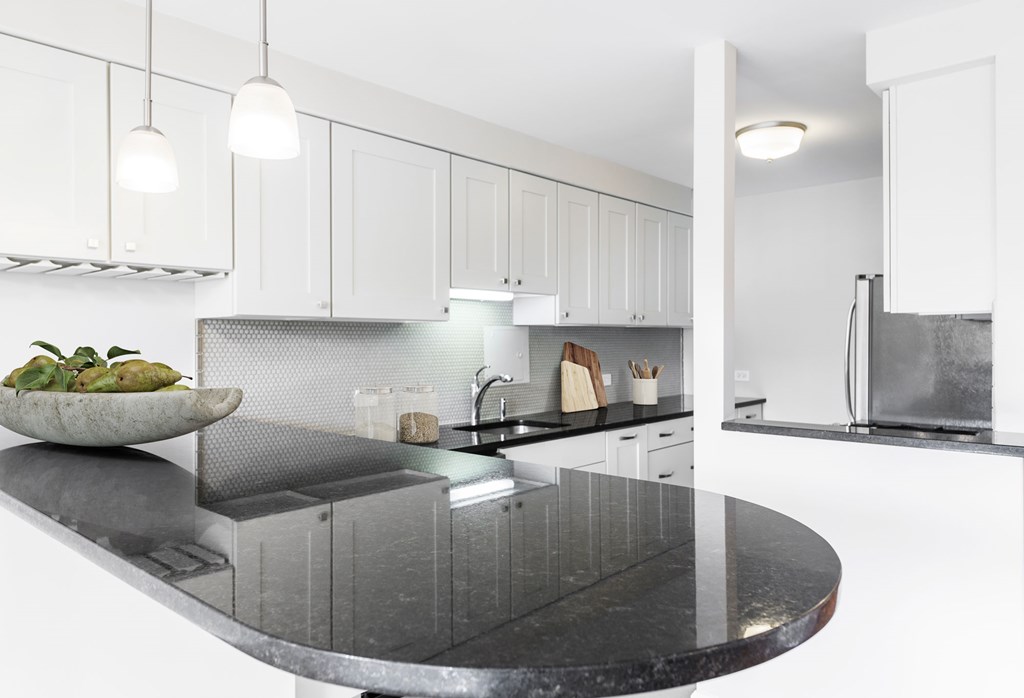 A modern kitchen with a black granite countertop and white cabinets.