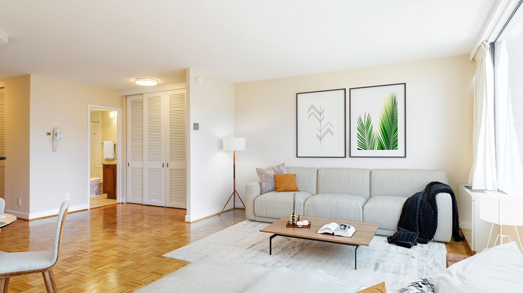 A living room with a white couch and a painting on the wall.
