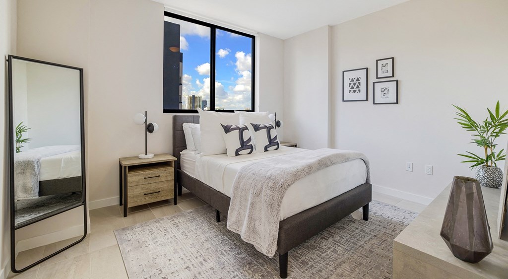 an apartment bedroom with a bed and a large window