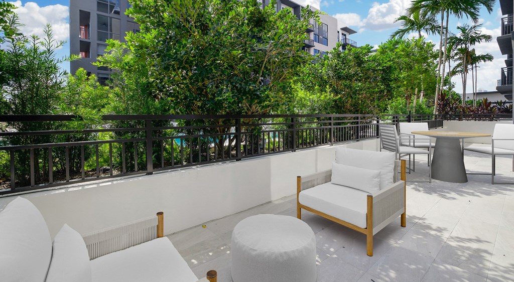 a patio with chairs and tables on a balcony with trees