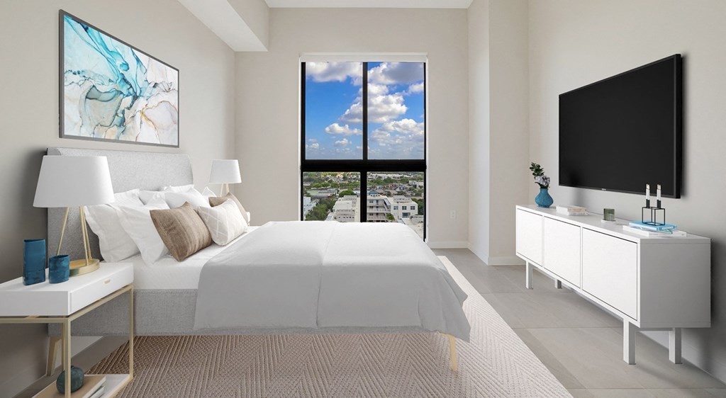 a white bedroom with a large bed and a tv