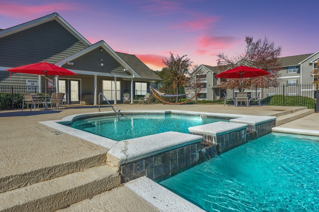 a swimming pool and patio with umbrellas in front of a house