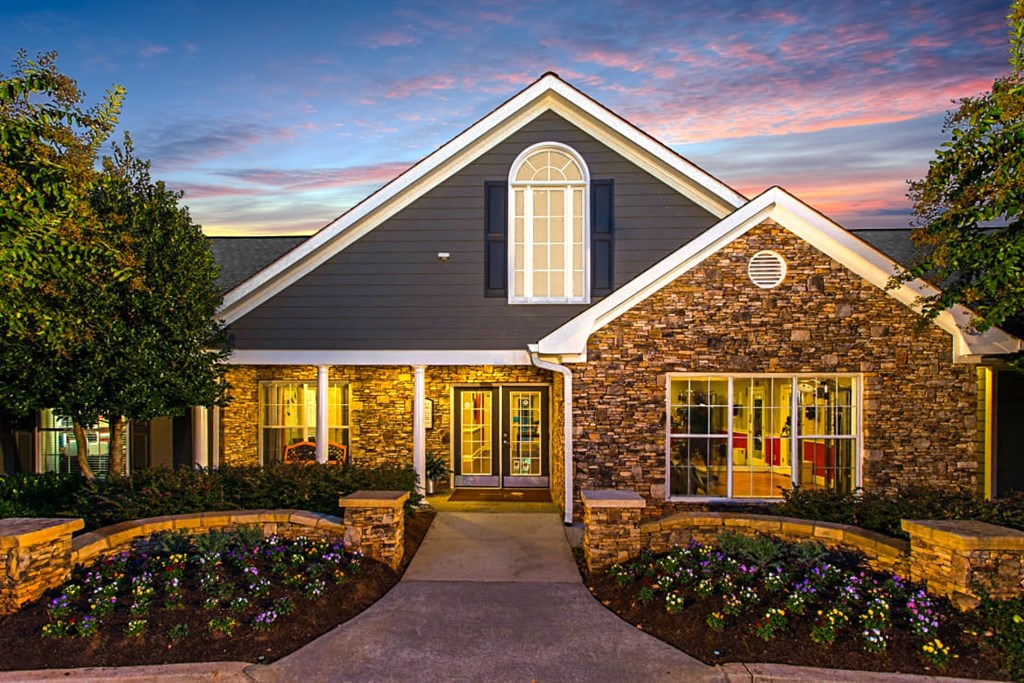 the exterior of a home at sunset with a driveway and a stone facade