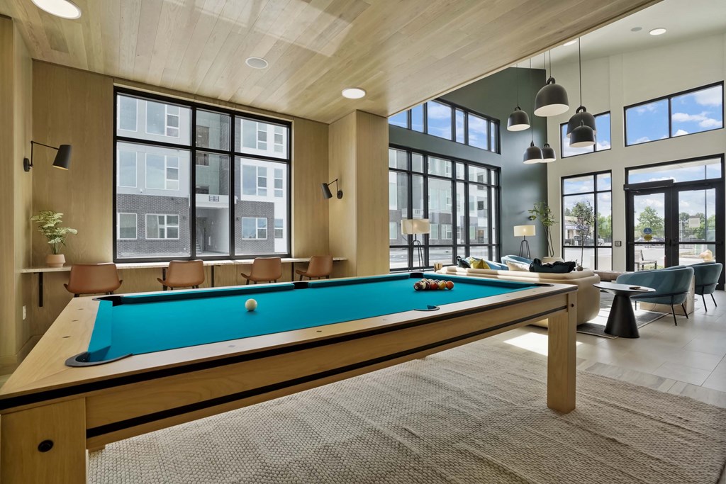 a pool table in a community room with windows
