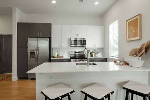a kitchen with a white counter top and a stainless steel refrigerator